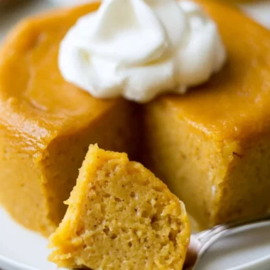 A slice of Crustless Pumpkin Pie Pudding served on a plate with whipped cream.