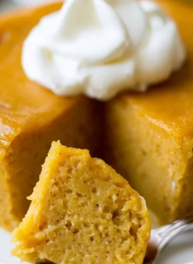 A slice of Crustless Pumpkin Pie Pudding served on a plate with whipped cream.