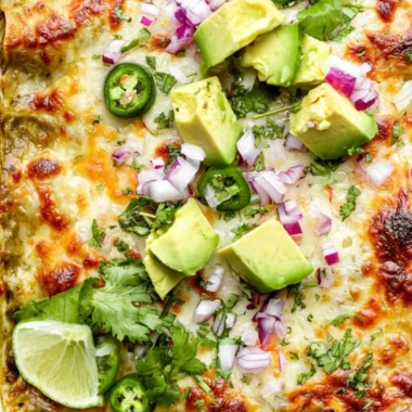 Delicious Green Chicken Enchilada Casserole topped with cheese and green sauce