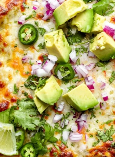 Delicious Green Chicken Enchilada Casserole topped with cheese and green sauce