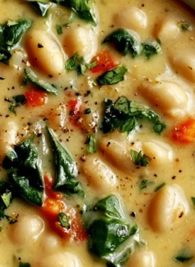 Bowl of high protein white bean soup garnished with herbs and spices.