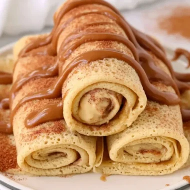 Delicious cinnamon roll protein crepes served with creamy topping and cinnamon drizzle.