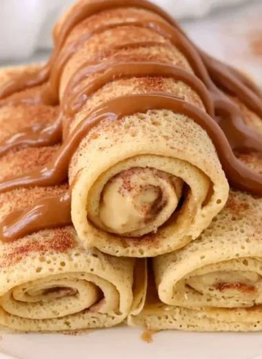 Delicious cinnamon roll protein crepes served with creamy topping and cinnamon drizzle.