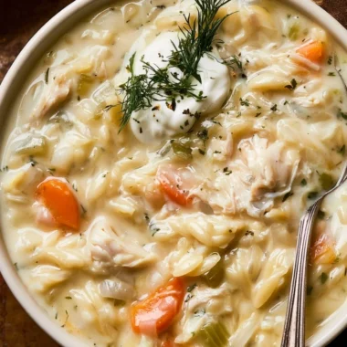 Bowl of creamy chicken orzo soup garnished with herbs