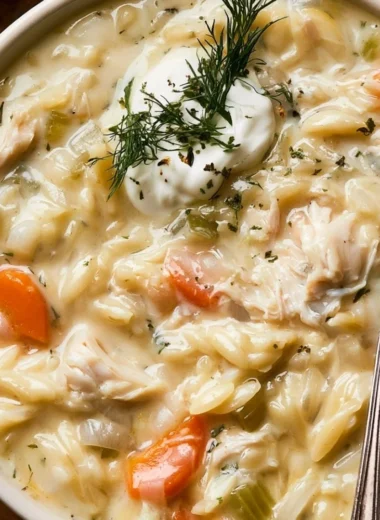 Bowl of creamy chicken orzo soup garnished with herbs